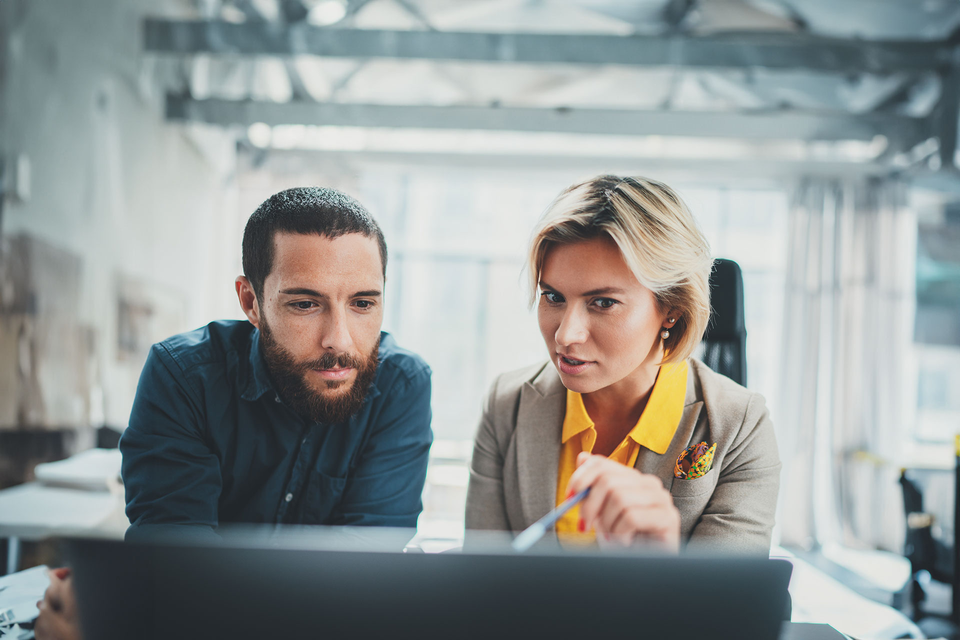 two people looking at a computer monitor and having a discussion.