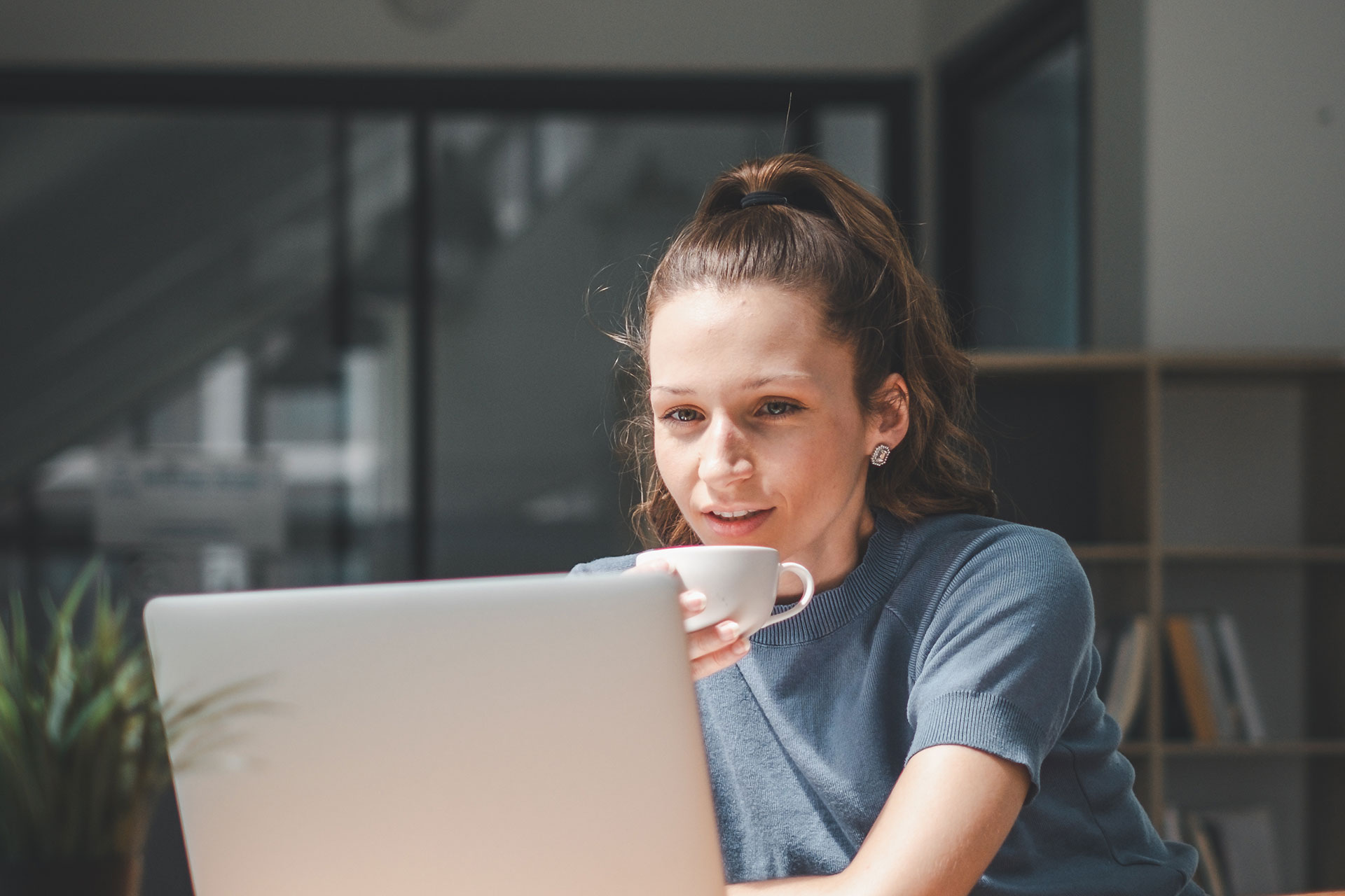 Woman viewing laptop while having coffee